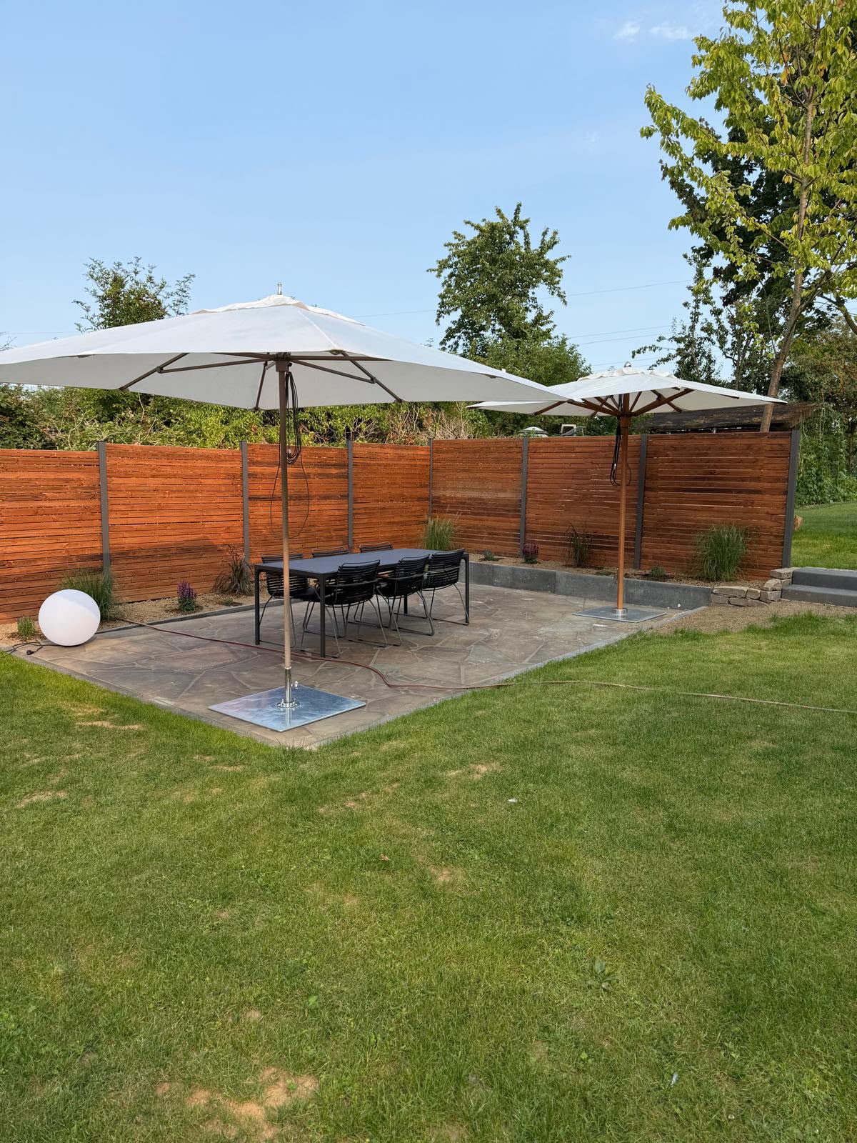 Terrasse mit Sonnenschirmen, Natursteinoptik und Holzsichtschutz in Meckenheim